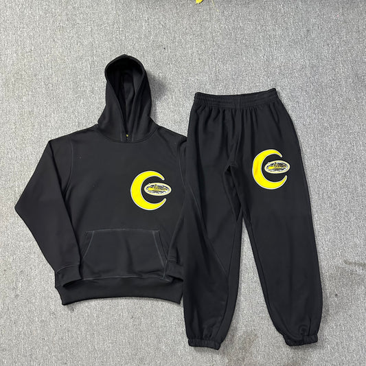 Black hoodie and pants set with yellow logo on a gray background